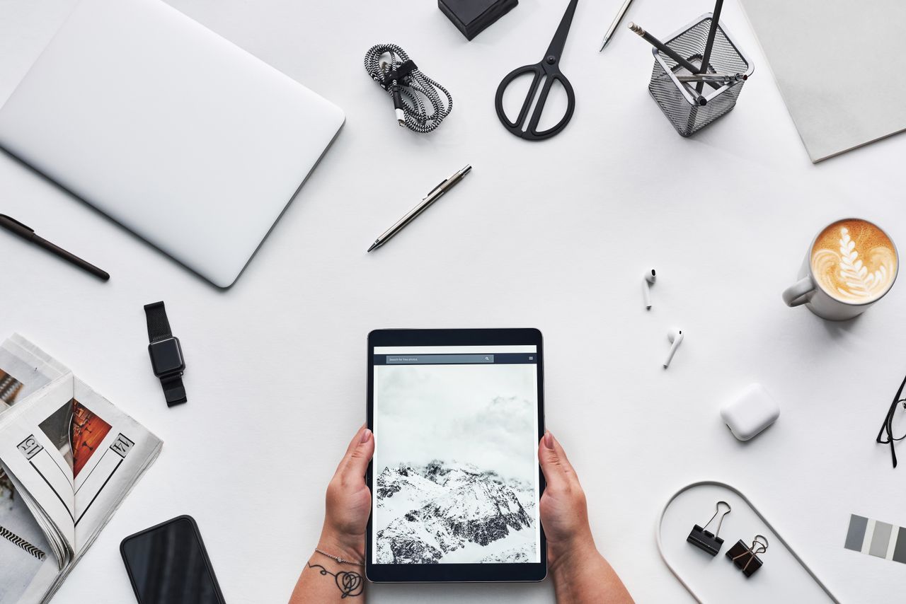 Flat lay of a modern workspace featuring a tablet, gadgets, and coffee for creative work.